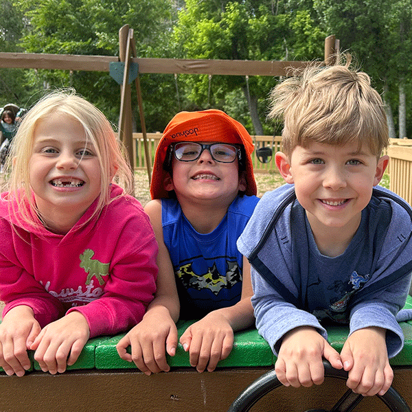 Three kids smiling at the playground