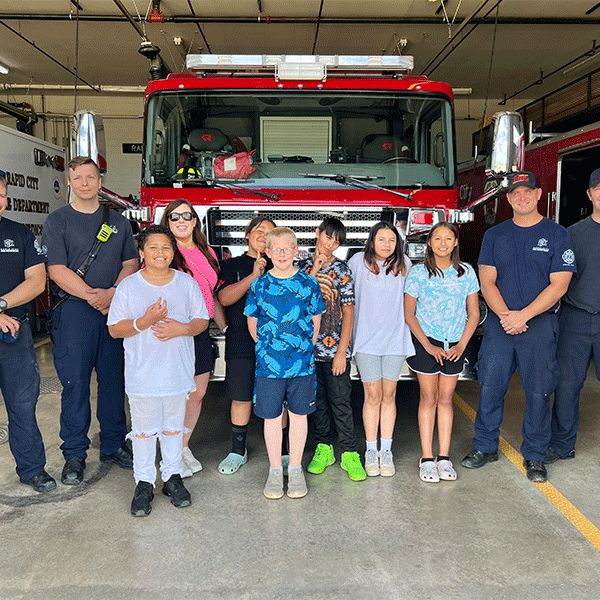 A group of students posing at the firestation with firemen
